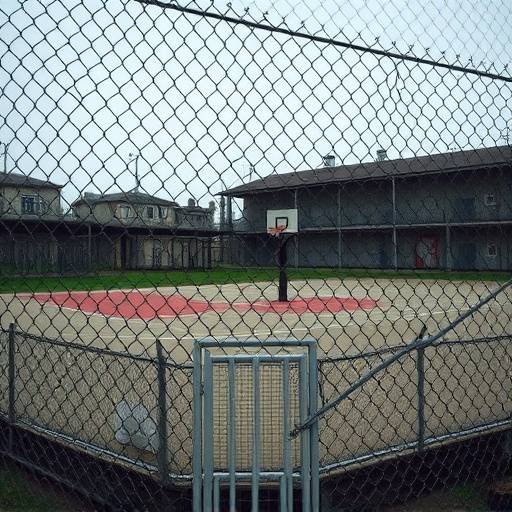 A prison yard with basketball court and chain-link fence.